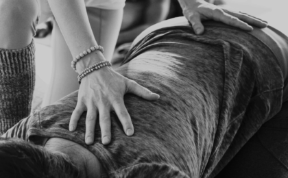 Yoga therapist shown with hands on the back of a woman prone in child's pose
